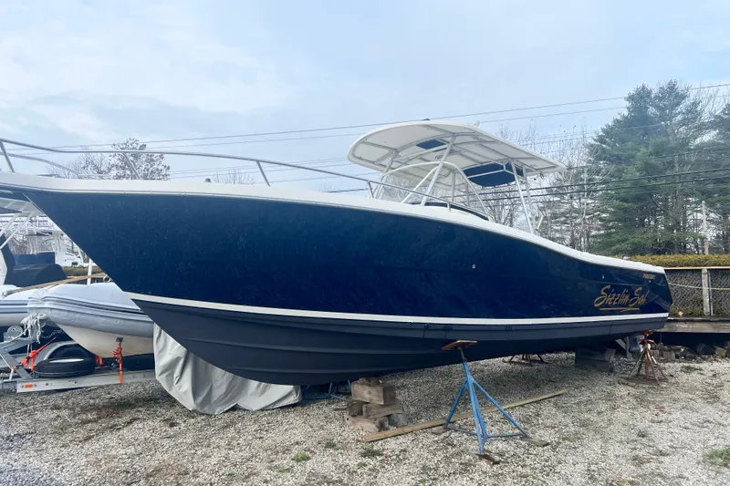 Slide: The Image of 2001 Pursuit 3070 Center Console boat on stands, blue hull, outdoor storage. - 51