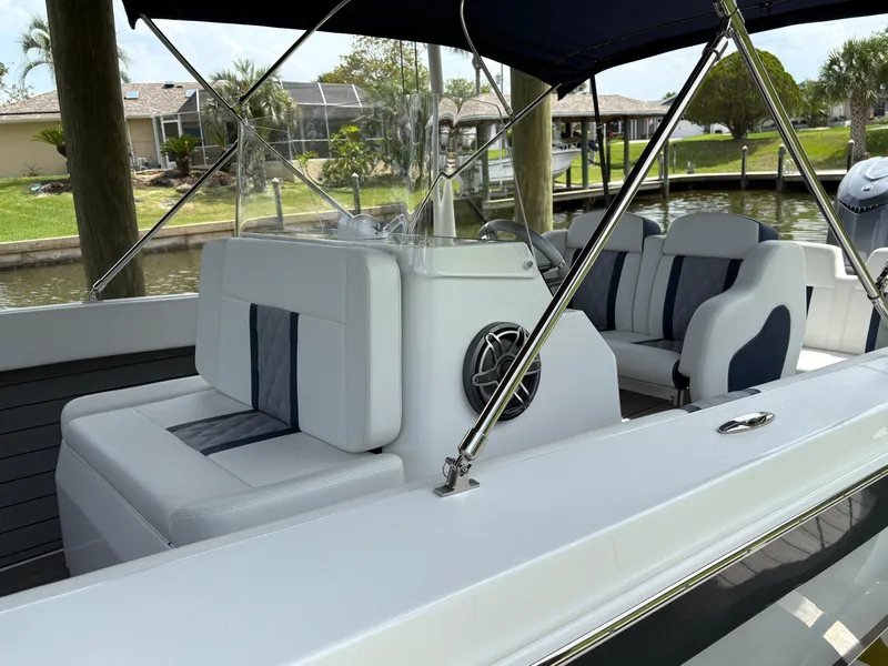 Slide: The Image of Luxury boat interior with white and blue seating, 2023 Action 25 model, docked by a canal. - 5