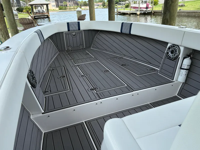 Slide: The Image of Interior of 2023 Action 25 boat with sleek gray flooring and seating by the water. - 4