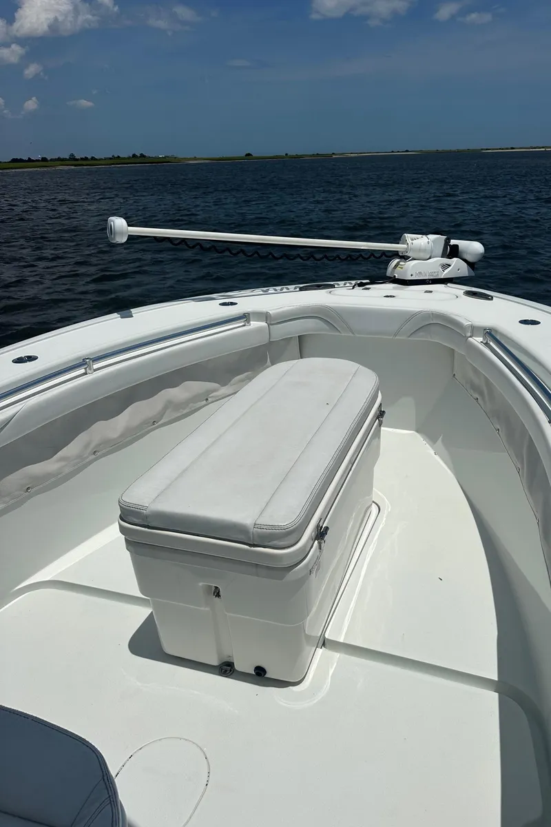 Slide: The Image of 2020 Yellowfin 26 Hybrid boat on calm water, featuring a spacious deck and seating. - 10