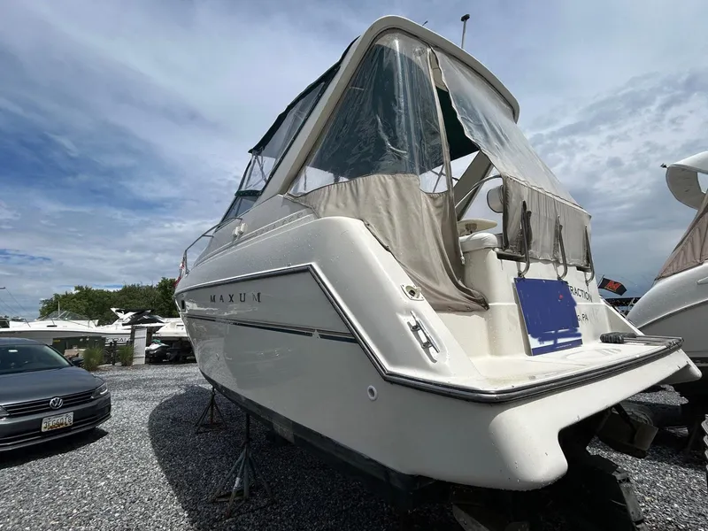 Slide: The Image of 1998 Maxum 2800 SCR boat on stands, with covered cockpit, parked outdoors. - 23