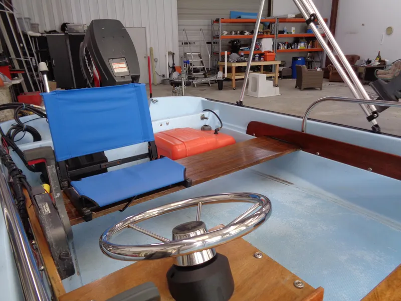Slide: The Image of 1964 Boston Whaler 13 Sport boat interior with blue seating and steering wheel in a garage. - 10