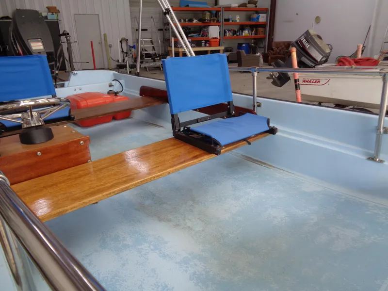 Slide: The Image of 1964 Boston Whaler 13 Sport interior with blue seats and wooden accents in a garage setting. - 11