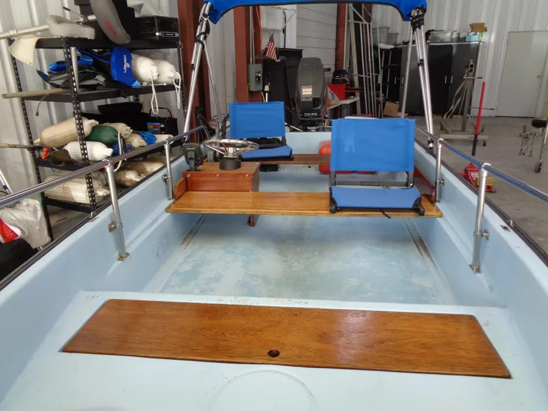 Slide: The Image of 1964 Boston Whaler 13 Sport boat interior with blue seats and wooden accents in a garage. - 3