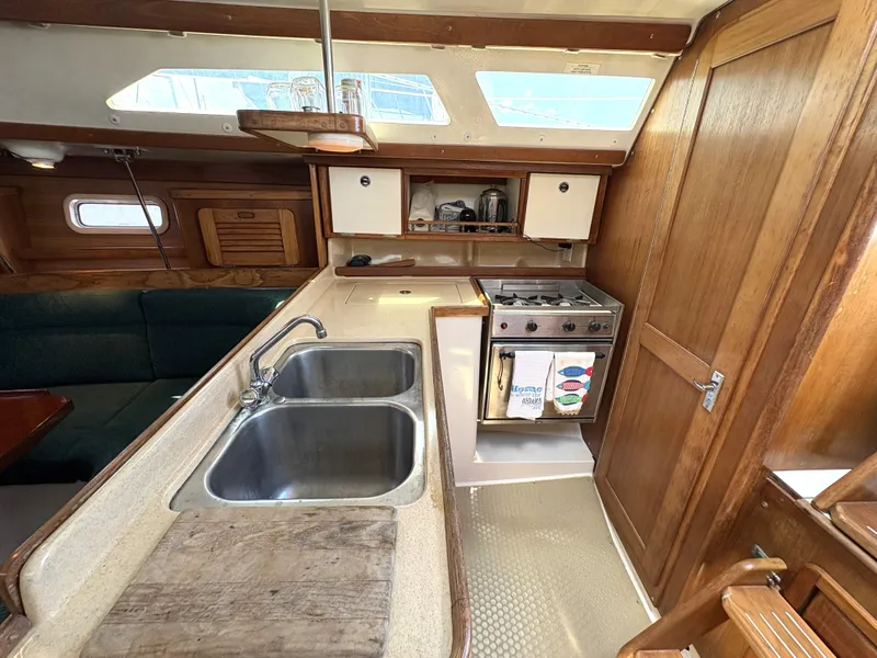 Slide: The Image of Interior of 1998 Catalina 34 MkII sailboat kitchen with sink, stove, and wooden cabinetry. - 18