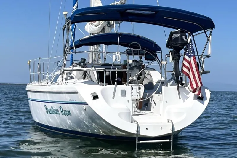 Slide: The Image of 1998 Catalina 34 MkII sailboat with American flag, anchored on calm water. - 3