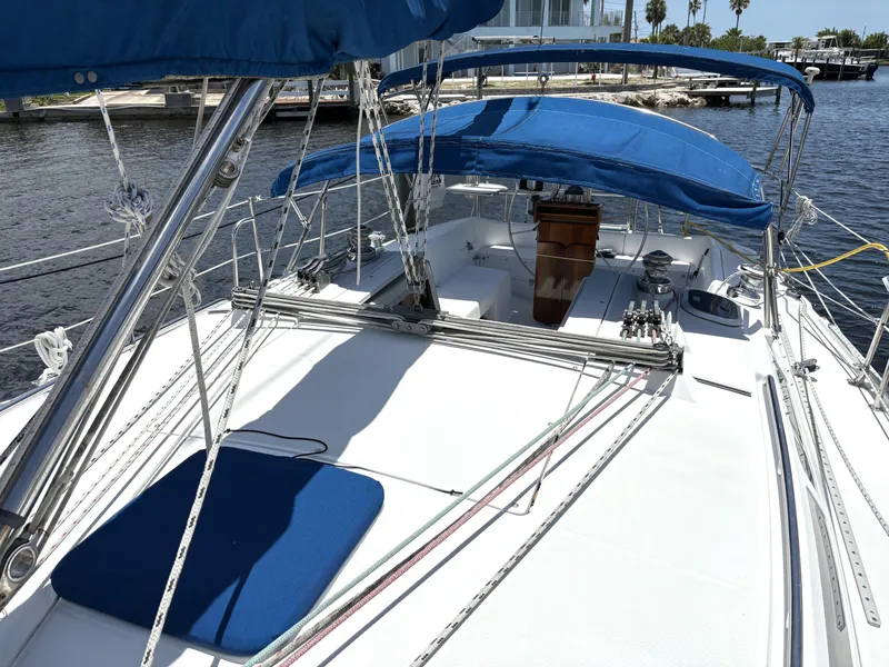 Slide: The Image of 1998 Catalina 34 MkII sailboat deck with blue canopy and rigging, docked by the water. - 6