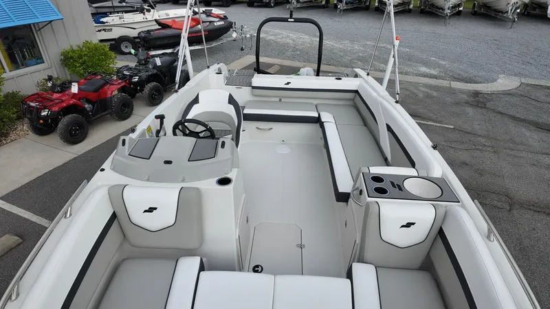 Slide: The Image of 2026 Starcraft SVX 211 OB boat interior with seating and steering wheel, parked near ATVs. - 18