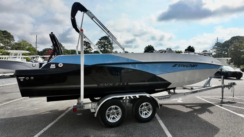 Slide: The Image of 2026 Starcraft SVX 211 OB boat on trailer, parked outdoors under cloudy sky. - 4