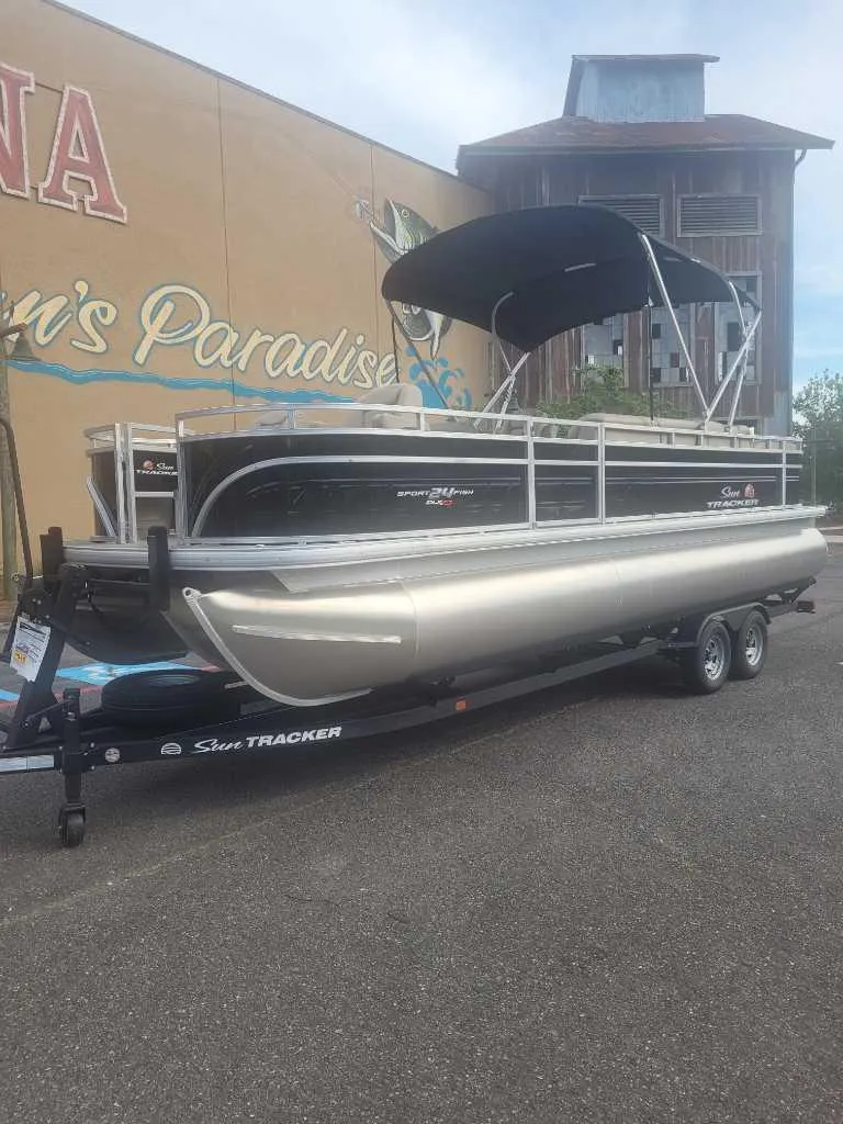 Slide: The Image of 2025 Sun Tracker Sportfish 24 XP3 pontoon boat on trailer, parked outdoors. - 10