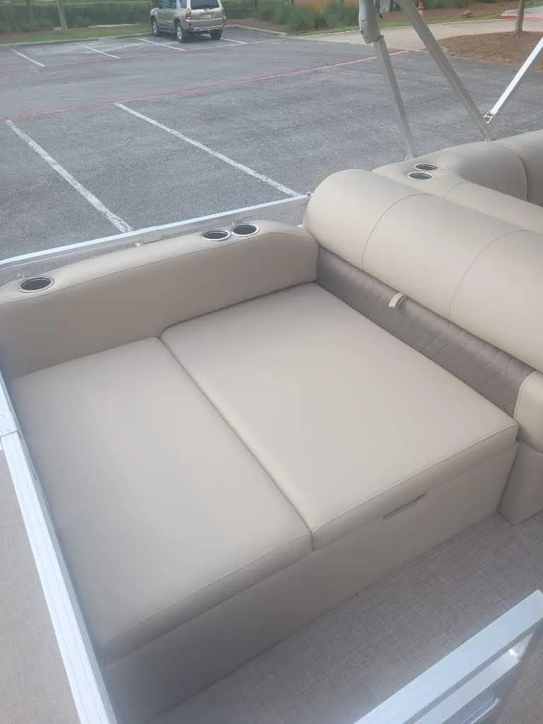 Slide: The Image of 2025 Sun Tracker Sportfish 24 XP3 boat interior with beige seating and cup holders. - 2