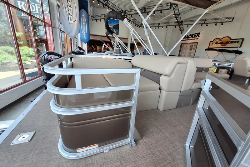 Slide: The Image of 2025 Sun Tracker Sportfish 24 XP3 pontoon boat interior with beige seating in showroom. - 9