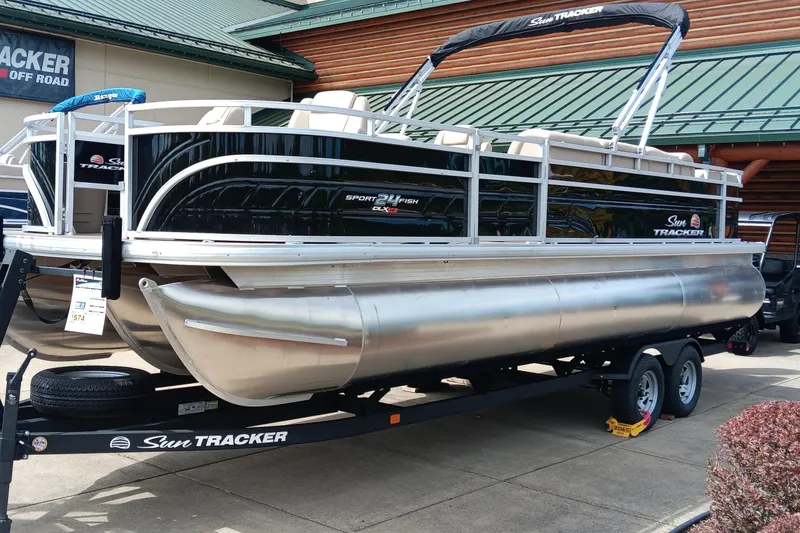 The Image of 2025 Sun Tracker Sportfish 24 XP3 pontoon boat on trailer, displayed outdoors. - 0