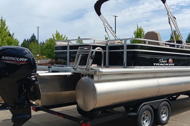 Slide: The Image of 2025 Sun Tracker Sportfish 24 XP3 pontoon boat with Mercury engine on trailer. - 2