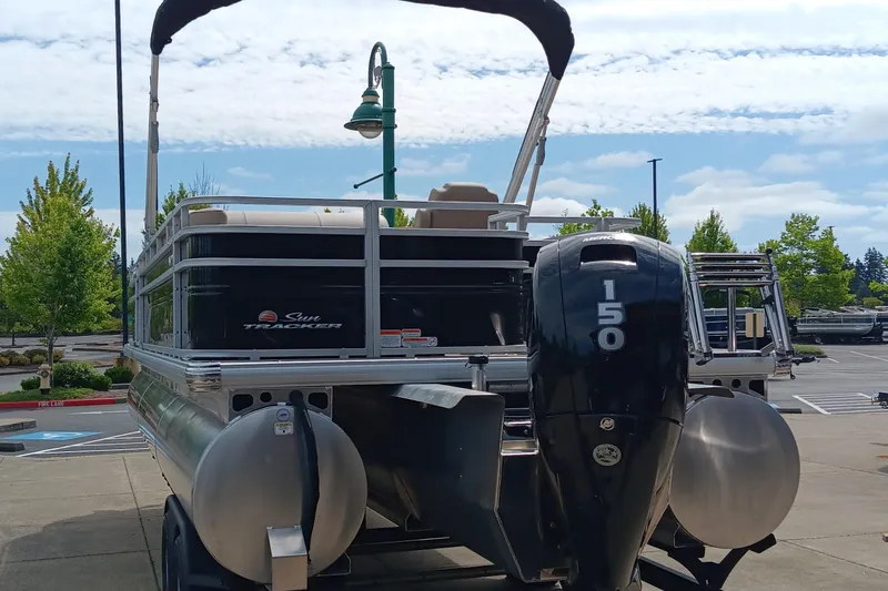 Slide: The Image of 2025 Sun Tracker Sportfish 24 XP3 pontoon boat with 150 HP engine, parked outdoors. - 3