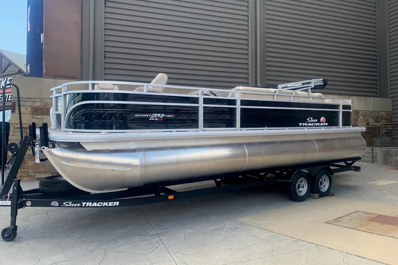 The Image of 2025 Sun Tracker Sportfish 24 XP3 pontoon boat on trailer, parked outdoors. - 0