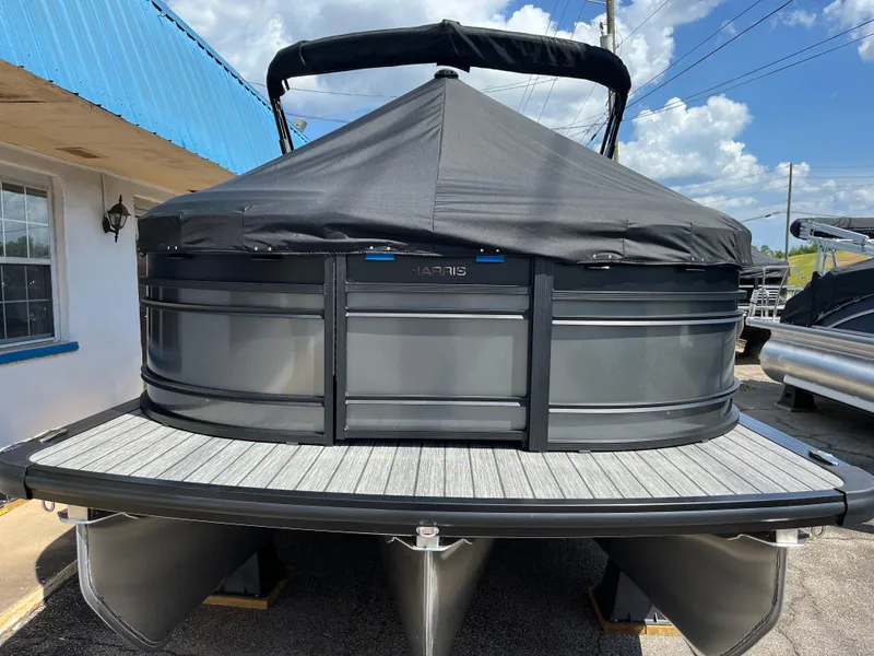 Slide: The Image of 2026 Harris Solstice 230 pontoon boat with black cover, docked under blue sky. - 2