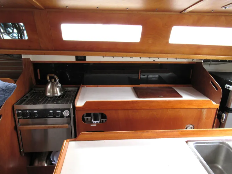 Slide: The Image of 1984 Santa Cruz 50 yacht interior kitchen with stove, kettle, and wooden cabinetry. - 14