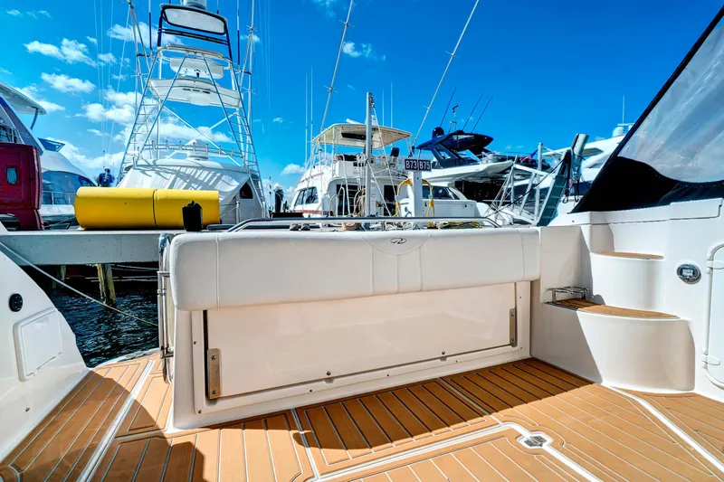 Slide: The Image of 2006 Regal 3560 COMMODORE yacht deck with seating, docked under clear blue sky. - 12