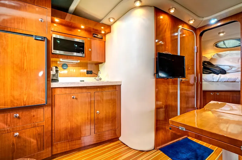 Slide: The Image of 2006 Regal 3560 COMMODORE yacht interior with wood cabinetry, kitchenette, and cozy sleeping area. - 18