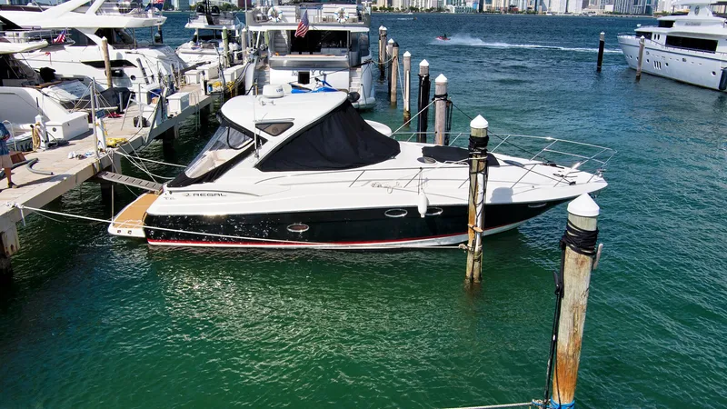 Slide: The Image of 2006 Regal 3560 COMMODORE yacht docked in a marina, surrounded by clear blue water. - 4