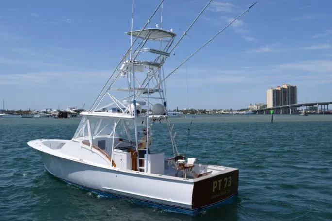 Slide: The Image of 1988 Rybovich Express Walkaround boat on water, clear sky, distant buildings. - 21