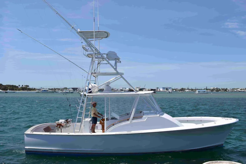 Slide: The Image of 1988 Rybovich Express Walkaround boat on water, clear sky, person onboard. - 22