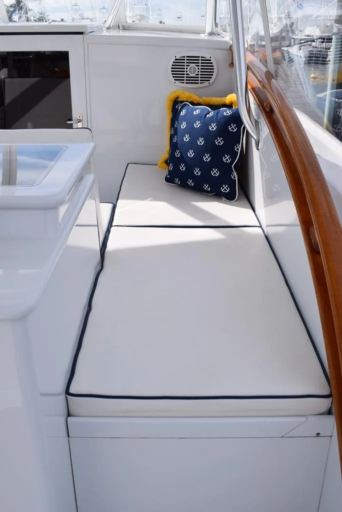 Slide: The Image of 1988 Rybovich Express Walkaround boat interior with cushioned seating and nautical-themed pillow. - 6