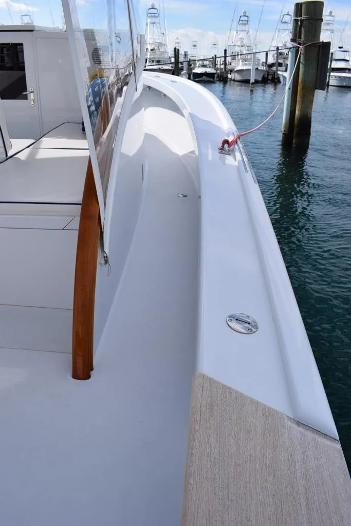 Slide: The Image of 1988 Rybovich Express Walkaround yacht docked, showcasing sleek deck design and marina background. - 7