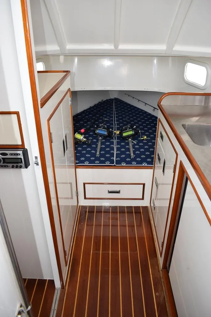 Slide: The Image of 1988 Rybovich Express Walkaround cabin interior with wood flooring and blue-patterned bedding. - 9