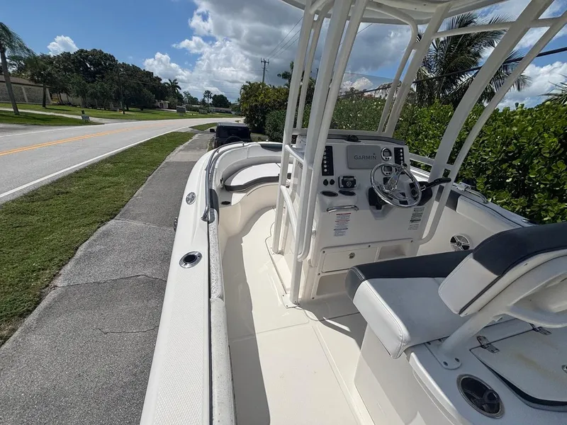 Slide: The Image of 2019 Robalo R222 Center Console boat parked on roadside, featuring helm and seating. - 12