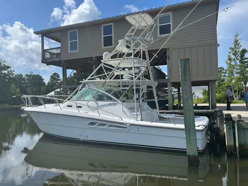 Slide: The Image of 2006 Rampage EXPRESS boat docked by a waterfront house under a clear blue sky. - 2