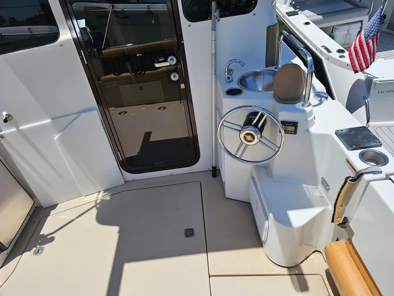 Slide: The Image of 2014 Ranger Tugs 31-CB cockpit with steering wheel, sink, and American flag. - 12