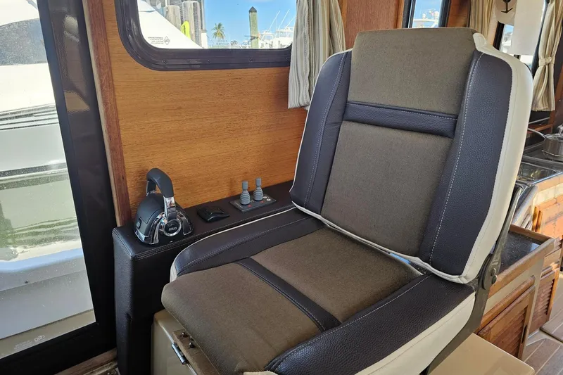 Slide: The Image of Captain's chair in 2014 Ranger Tugs R 31 boat interior, featuring control panel and window view. - 33