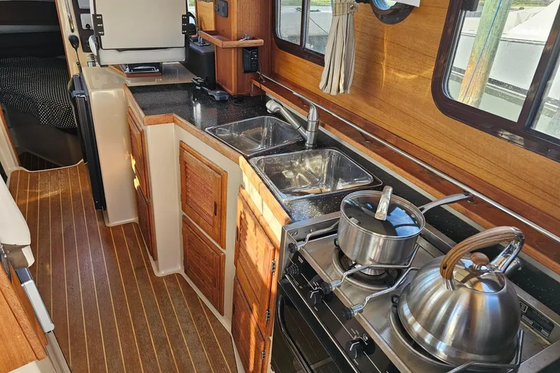 Slide: The Image of 2014 Ranger Tugs R 31 boat kitchen with stove, sink, and wooden cabinetry. - 37