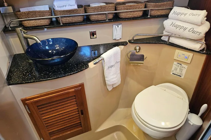 Slide: The Image of 2014 Ranger Tugs R 31 bathroom with blue sink, toilet, and "Happy Ours" towels. - 43