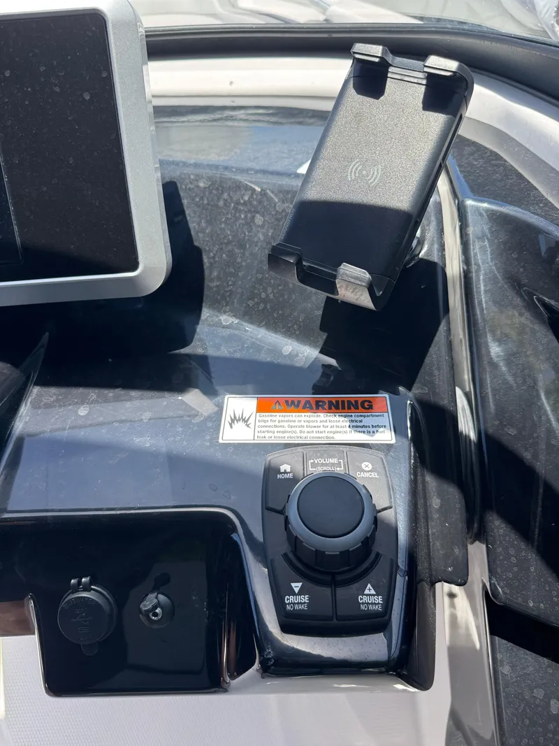 Slide: The Image of Control panel of 2025 Yamaha Boats AR250 with warning label and phone holder. - 24