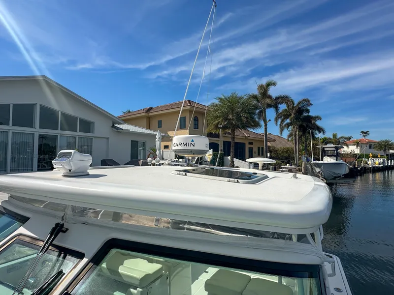Slide: The Image of 2006 Tiara Yachts 3200 Open docked near waterfront homes under a clear blue sky. - 12