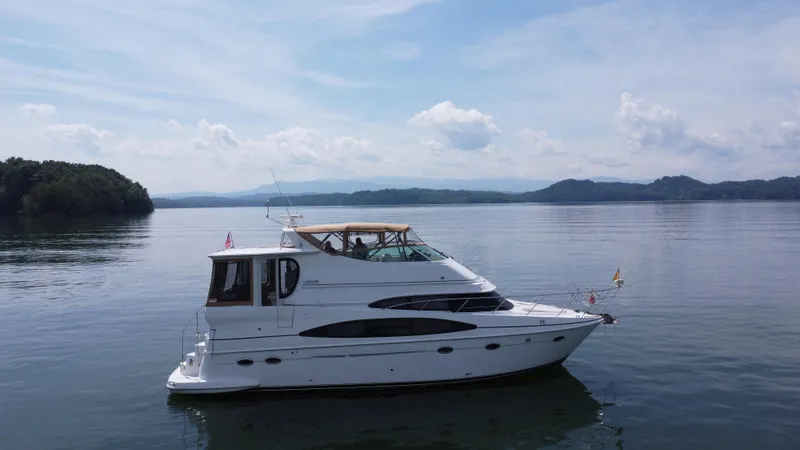 Slide: The Image of 2002 Carver 466 Motor Yacht cruising on a serene lake under a clear sky. - 2