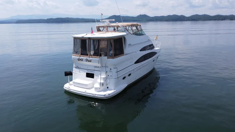 Slide: The Image of 2002 Carver 466 Motor Yacht on calm water with scenic mountain backdrop. - 3