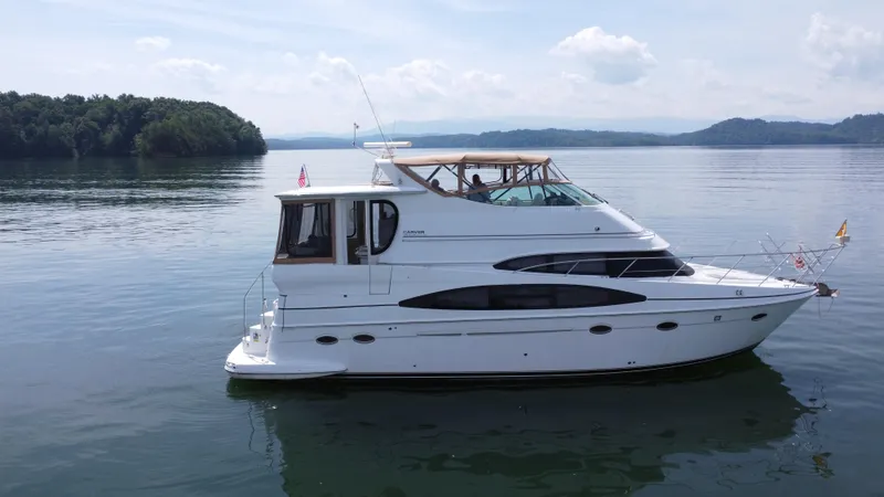 Slide: The Image of 2002 Carver 466 Motor Yacht on serene lake with lush green shoreline. - 7