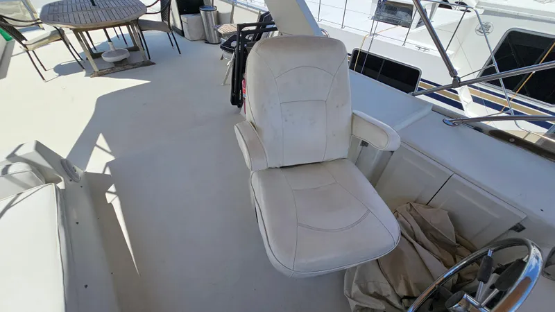 Slide: The Image of Captain's chair on 1988 Bluewater Yachts 55 Coastal Cruiser deck, with table and chairs nearby. - 10