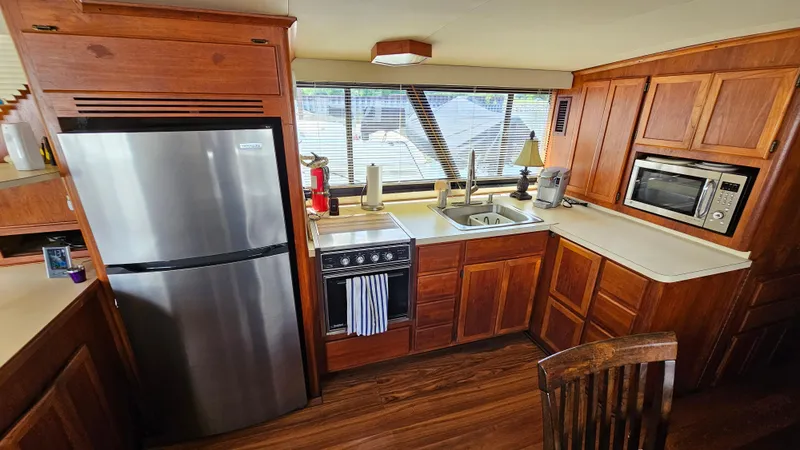 Slide: The Image of 1988 Bluewater Yachts 55 Coastal Cruiser kitchen with wood cabinets, stainless steel appliances, and large windows. - 18