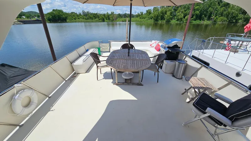 Slide: The Image of 1988 Bluewater Yachts 55 Coastal Cruiser deck with seating, table, and scenic river view. - 5