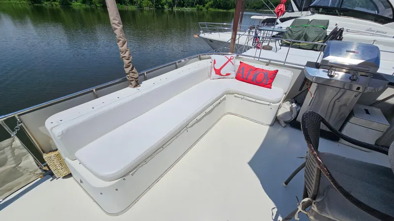 Slide: The Image of 1988 Bluewater Yachts 55 Coastal Cruiser deck with seating, grill, and decorative pillows. - 6