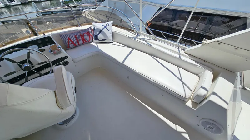 Slide: The Image of 1988 Bluewater Yachts 55 Coastal Cruiser helm with white seating and nautical-themed pillows. - 9