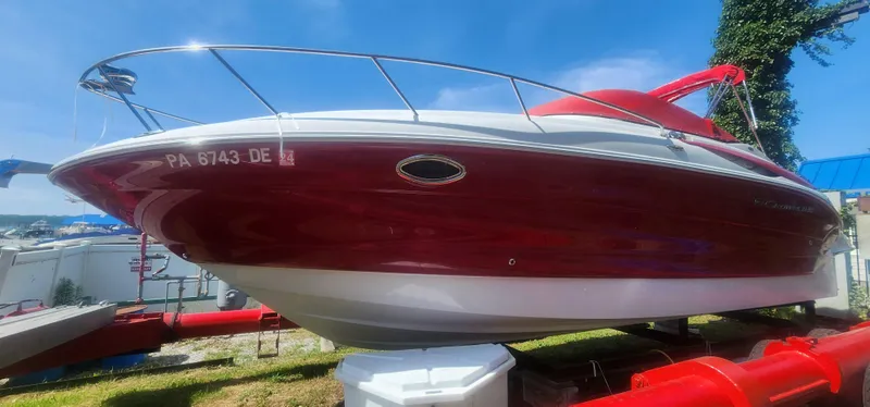 Slide: The Image of 2009 Crownline 250CR boat with red and white exterior on display outdoors. - 2
