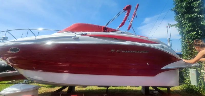Slide: The Image of 2009 Crownline 250cr boat with red and white exterior on display outdoors. - 29