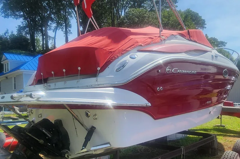 Slide: The Image of 2009 Crownline 250CR boat with red cover, parked on trailer, sunny day. - 3