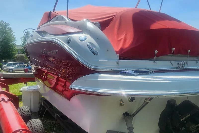 Slide: The Image of 2009 Crownline 250CR boat with red cover on trailer, parked outdoors. - 30